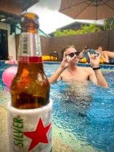 mężczyzna w basenie z butelką piwa w obiekcie K-Bunk Hostel Pai Walking Street w mieście Pai