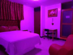 Hostal Reyna في ليما: غرفة نوم مع سرير وطاولة مع ضوء أرجواني
