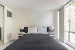 a white bedroom with a large bed with two tables at New Luxury Apartment WeHo Boys Town in Los Angeles