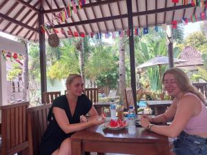 Dos mujeres sentadas en una mesa en un restaurante en Banana Leaf Resort, en Gili Trawangan