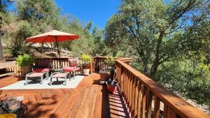 a wooden deck with chairs and an umbrella at Yosemite Mountain Retreat in Oakhurst