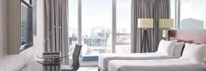um quarto de hotel com uma cama e uma cadeira e uma janela em Cordis, Hong Kong em Hong Kong