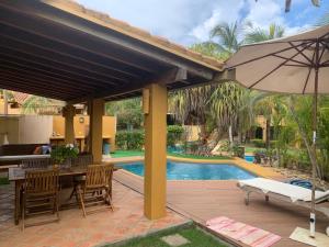 a patio with a table and an umbrella and a pool at Morrocoy - Acogedora Casa VIP Tucacas in Tucacas