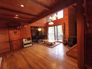 a large living room with wooden floors and a large window at 木香苑 in Tsumagoi