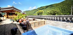 uma piscina ao lado de um edifício com uma montanha em Danyang Hanok 단양한옥가대리 em Danyang