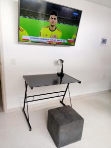 a table with a television hanging on a wall at Aparta estudio NUEVO- zona centrica de Bucaramanga in Bucaramanga
