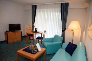 Una sala de estar con un sofá azul y una mesa. en Landhotel Imhof, en Neuhof