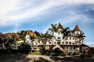 ein großes weißes Gebäude mit Palmen davor in der Unterkunft Grande Hotel Glória in Águas de Lindóia