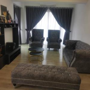 uma sala de estar com um sofá e duas cadeiras e uma mesa em Sitiawan Acacia Homestay em Sitiawan