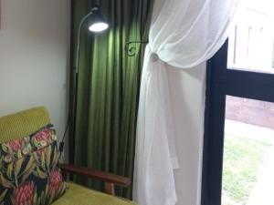 a bedroom with a bed and a window with green curtains at Fynbos Single Stay in Langebaan