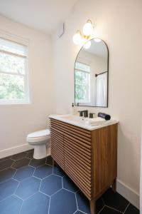 a bathroom with a sink and a mirror and a toilet at Newly Reno'd Historic Mansion 1 Mile to UF & DT in Gainesville