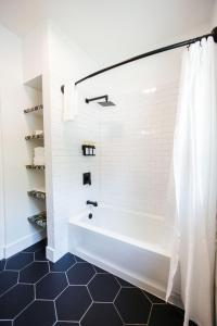 a white bath tub in a bathroom with a black floor at Newly Reno'd Historic Mansion 1 Mile to UF & DT in Gainesville
