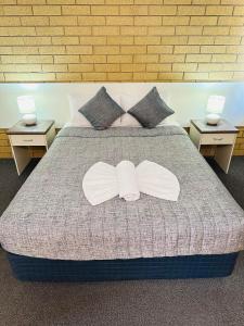 a large bed with two white bows on it at Mundubbera Motel in Mundubbera +49 photos