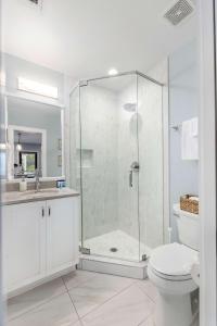 uma casa de banho branca com um chuveiro e um WC. em Private Balcony 2 Living Rooms 2 Blocks to King em Charleston