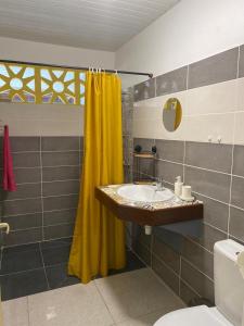 baño con lavabo y cortina de ducha amarilla en ST-Laurent Haut de Balate Confort, en Saint-Laurent-du-Maroni