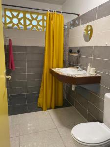 La salle de bains est pourvue d'un rideau de douche jaune et d'un lavabo. dans l'établissement ST-Laurent Haut de Balate Confort, à Saint-Laurent du Maroni