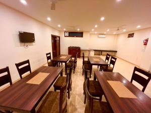 comedor con mesas y sillas de madera en Hotel Olive Vault, Most Awarded Property in Haridwar, en Haridwar