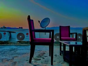 Hotel Olive Vault, Most Awarded Property in Haridwar في حاريدوار: زوج من الكراسي وطاولة على الشاطئ