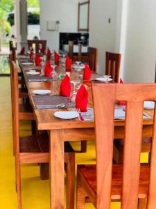 una larga mesa de madera con servilletas rojas. en Yala River Front Hotel & Restaurant, en Tissamaharama