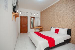 - une chambre avec un lit et une couverture rouge dans l'établissement RedDoorz Syariah near Jatisampurna Hospital, à Bekasi