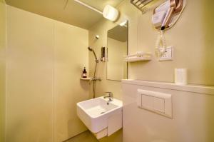 ein weißes Badezimmer mit einem Waschbecken und einem Spiegel in der Unterkunft Men Tang Hotel in Shanghai