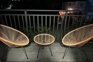 tres sillas de ratán sentadas en un balcón por la noche en Modern 2 Bed Furnished Apartment in Quincy, en Quincy