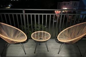 Tres sillas de ratán sentadas en un balcón por la noche. en Modern 2 Bed Furnished Apartment in Quincy, en Quincy
