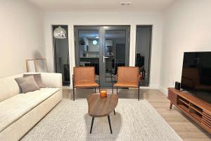 sala de estar con sofá, TV y sillas en Modern 2 Bed Furnished Apartment in Quincy, en Quincy