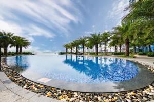 a large swimming pool with palm trees and a beach at Muong Thanh Luxury Ha Long Centre II in Ha Long