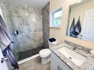 a bathroom with a shower and a toilet and a sink at Palm Beach Cottage in West Palm Beach +32 photos