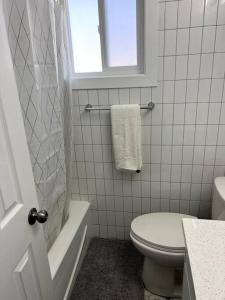 a white bathroom with a toilet and a window at Walking distance to St Boniface, easy parking in Winnipeg
