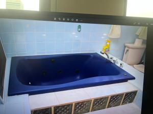 y baño con aseo y bañera azul. en Jamaica Villa By The Sea, en Saint Mary