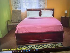 1 dormitorio con 1 cama grande con colcha rosa en Jamaica Villa By The Sea, en Saint Mary
