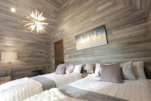 OiwakeにあるSAUNAFORESTCABIN軽井沢御代田zenasobi棟のベッド2台、木製の壁、シャンデリアが備わる客室です。