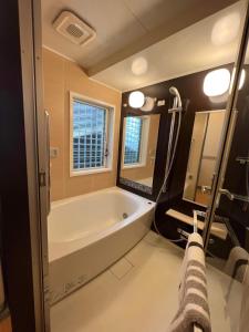 a bathroom with a bath tub and a large mirror at 横浜 JS HOUSE Yokohama - ペット犬可 in Yokohama