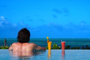 Ein Mann im Schwimmbad mit einem Drink. in der Unterkunft Belvedere Resort in Jambiani