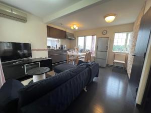a living room with a blue couch and a kitchen at 横浜 JS HOUSE Yokohama - ペット犬可 in Yokohama