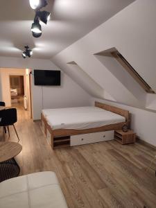 a bedroom with a bed and a tv in a attic at Apartmán Tulipán in Hnúšťa