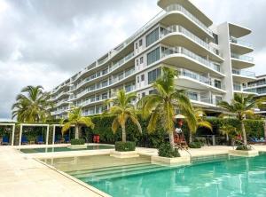 a large apartment building with palm trees and a swimming pool at Morros io Manzanillo, sensacional apartamento tipo Loft, salida directa a playa in La Siriaca