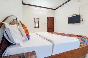 Schlafzimmer mit einem Bett und einem TV an der Wand in der Unterkunft Hotel Orchid Inn in Udagamandalam