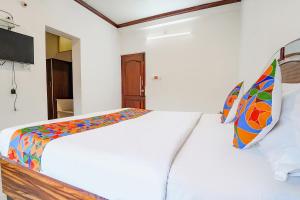een witte slaapkamer met een bed met een kleurrijk dekbed bij Hotel Orchid Inn in Ooty