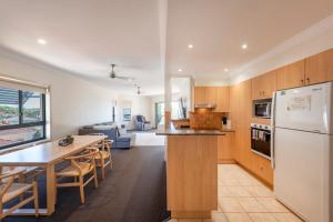 a kitchen and living room with a table and a refrigerator at Breakers 1 8 LJHooker Yamba in Yamba