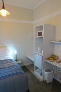 sypialnia z łóżkiem, biurkiem i kuchenką mikrofalową w obiekcie Two Palms w mieście Gisborne
