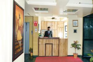 un hombre parado en un mostrador en una habitación en hotel suraj classic, en Pune