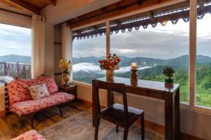 a room with a table and a chair and a large window at SaffronStays The Clairmont Cottage,Mukteshwar in Mukteshwar