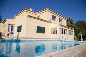 a villa with a swimming pool in front of a house at Quinta do Pinheiral in Lagos