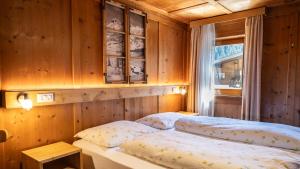 two beds in a room with wooden walls and a window at Chalet Funtanacia in La Villa