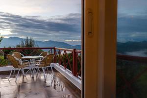 a balcony with a table and chairs and mountains at SaffronStays The Clairmont Cottage,Mukteshwar in Mukteshwar