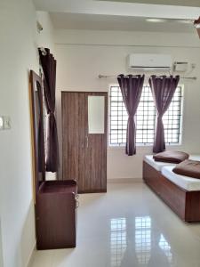 1 dormitorio con 2 camas en una habitación con ventanas en Suvarna Grande Homes en Mangalore