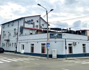 a white building on the corner of a street at Pensiunea Luisa in Craiova